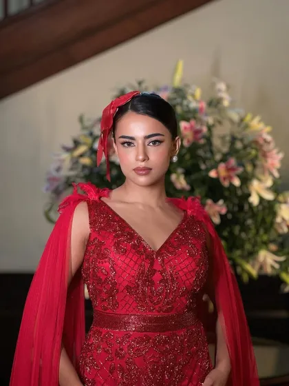 A confident and striking portrait. The monochrome red theme is carried through from the outfit to the makeup, creating a cohesive and powerful look.