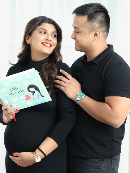 Reading a book titled "Little Miracle" together is a sweet and symbolic activity to include in your maternity photoshoot.