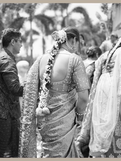 A timeless black and white photo capturing the bride from behind, showcasing her traditional hairstyle adorned with flowers.