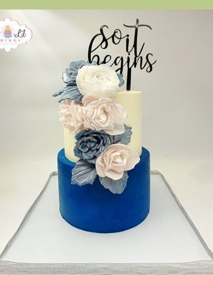 "So it begins." A chic two-tiered cake with a deep blue velvet bottom tier and a cascade of handcrafted sugar flowers.