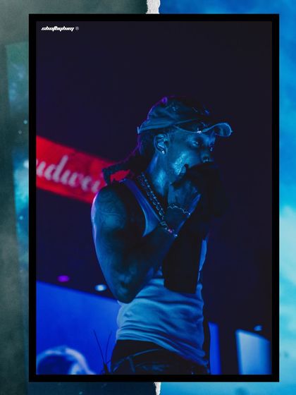 A moody, blue-lit shot of Wiz Khalifa performing at Rolling Loud, with the Budweiser sponsor banner visible in the background.