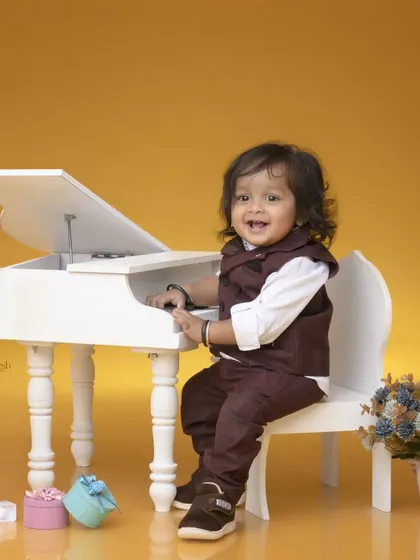 A little musician celebrating his first birthday at a miniature piano. His joyful expression and smart outfit make for a perfect milestone photograph.