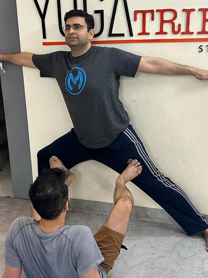 This partner-assisted Warrior II against our studio logo wall creates a powerful image of strength and community.