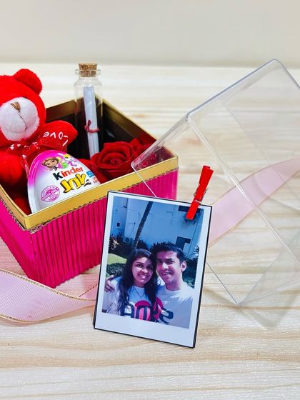 An affordable and personal Valentine's gift. This mini hamper includes a polaroid photo, a teddy bear, a Kinder Joy, a message in a bottle, and an artificial rose.