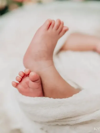 A beautifully composed shot of newborn feet, with the baby's face softly blurred in the background. This artistic focus draws all attention to just how small and perfect those feet are.