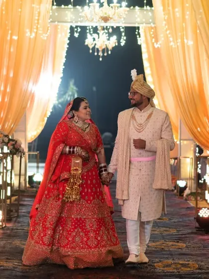 Walking into their future together, framed by beautiful wedding decor. This is a classic wedding day photograph that feels both grand and personal.