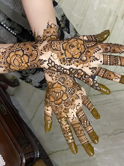 This design showcases a bolder, Arabic-inspired floral style. The prominent rose patterns on both the front and back of the hands create a striking look with beautiful negative space, perfect for the modern bride.