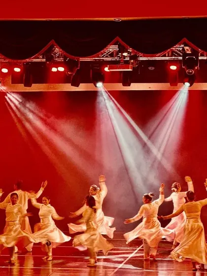 The dancers in motion during the Indian Fusion performance, with their white skirts creating beautiful patterns under the dramatic stage lighting.
