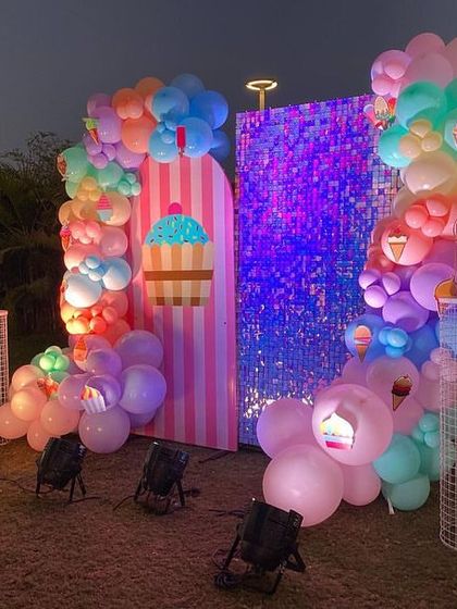 The Candyland photo booth lit up at night, with spotlights enhancing the vibrant colors of the balloons and backdrops.
