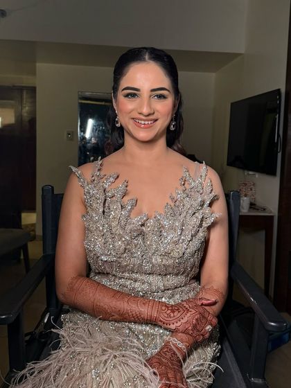 The bride seated, looking radiant in her glamorous reception gown. The makeup enhances her features and gives her a beautiful, confident glow.