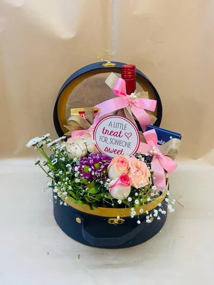 A sweet treat for someone sweet. This charming round trunk box is filled with fresh flowers, wine, and chocolates, making it a perfect romantic gift.