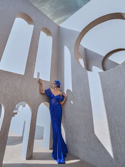 A sculpted mesh gown in active blue, featuring a striking shoulder structure, corseted precision, and front-gathered elegance. A prism of power, illuminated in a bold hue.
