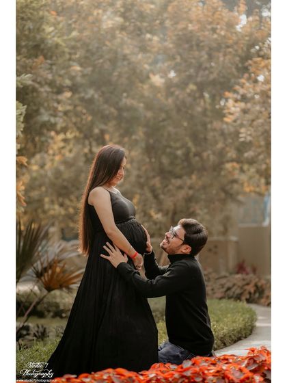 Another take on the dad-to-be connecting with the bump, this time in a beautiful garden setting with colorful flowers in the foreground.