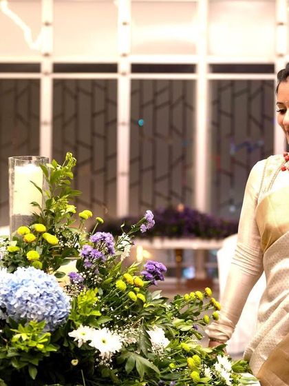 A candid shot of Pooja, highlighting the beautiful floral decor and her graceful white and gold saree look.