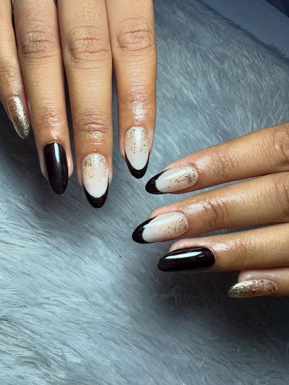 A chic and moody set with a mix of black French tips, glossy black nails, and gold glitter accents.