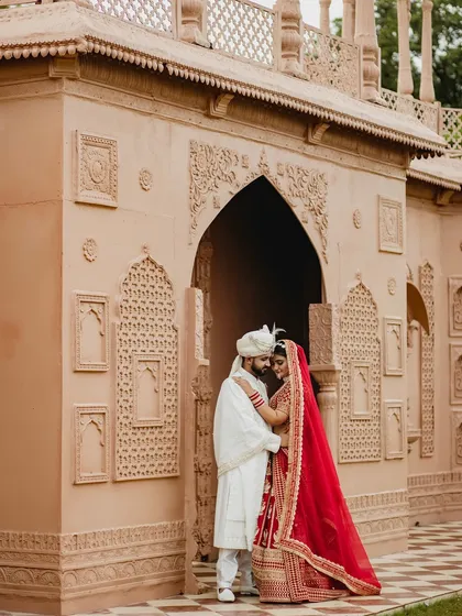 An intimate portrait of the couple framed by an ornate archway. The groom's embrace and their close proximity create a feeling of love and protection.