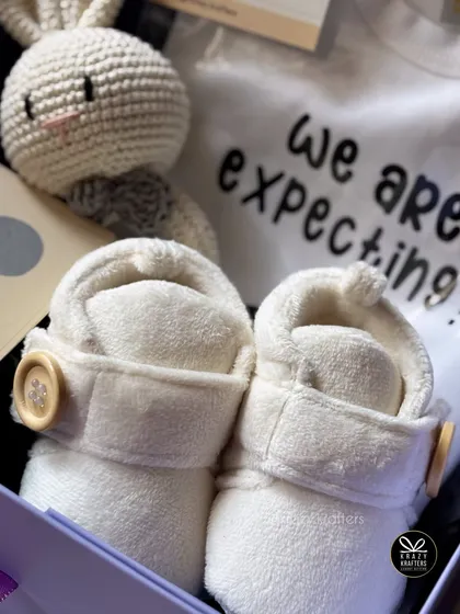 "We are expecting!" This hamper gets straight to the point with a custom onesie, adorable buttoned baby booties, and a crochet bunny rattle.