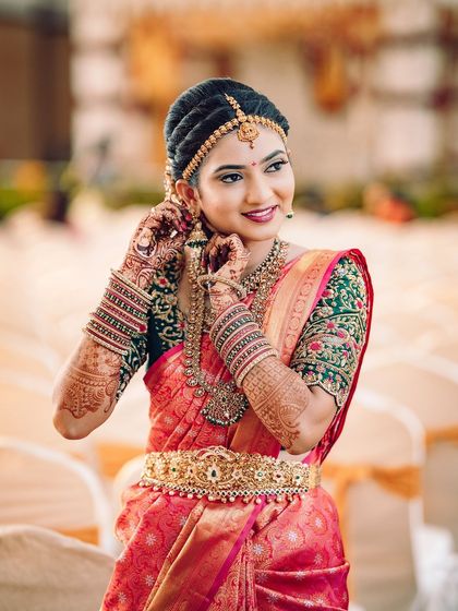 A candid moment of the bride adjusting her earring, showing the detailed jewellery and flawless makeup up close.