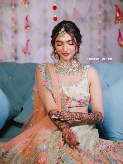 A bride looking down at her hands, admiring the intricate mehandi that we created for her.