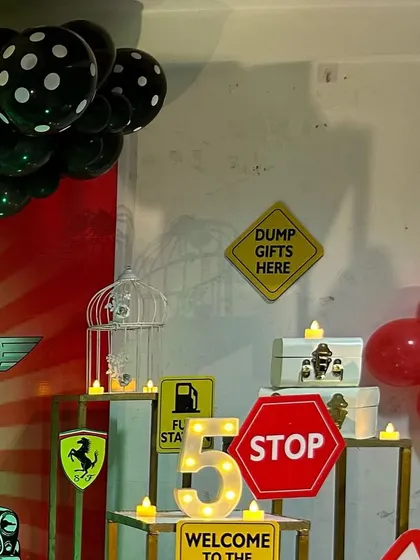 Fun and thematic props for a car-themed party, including road signs like 'Dump Gifts Here'.