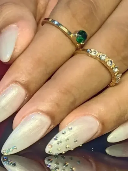 A close-up of the rhinestone cascade on the elegant pearly white nails.