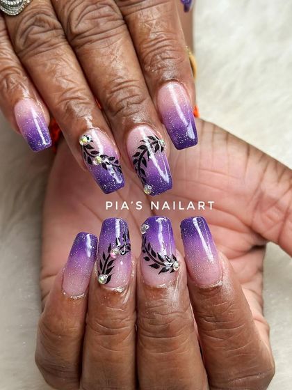 Perfect nails for Karwa Chauth. This set features a purple glitter ombre with delicate black leaf art and rhinestone accents.
