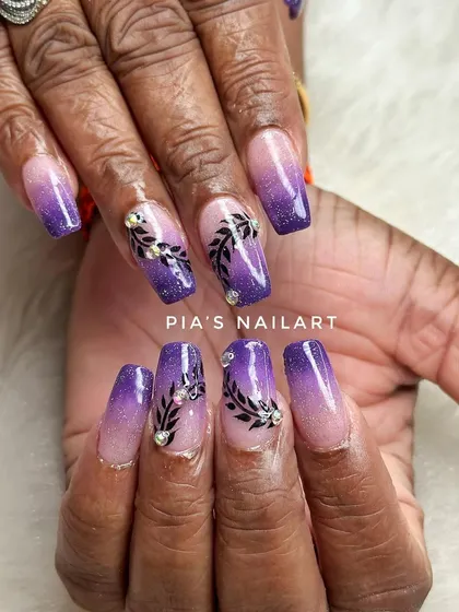Perfect nails for Karwa Chauth. This set features a purple glitter ombre with delicate black leaf art and rhinestone accents.