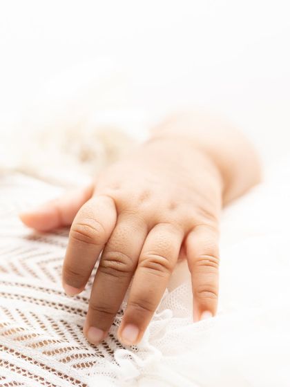 A macro photo of a newborn's tiny hand, showing the delicate lines and wrinkles. These are the details you'll want to hold onto forever.