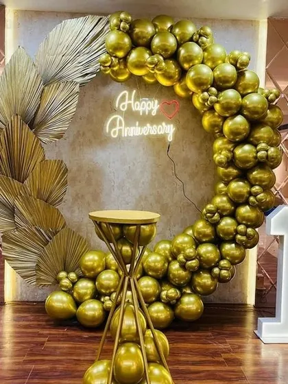 A classic and elegant 1st anniversary celebration. The all-gold balloon ring, accented with dried palm leaves and a neon sign, creates a luxurious and romantic photo spot. The light-up number '1' and custom cake stand complete this beautiful setup.