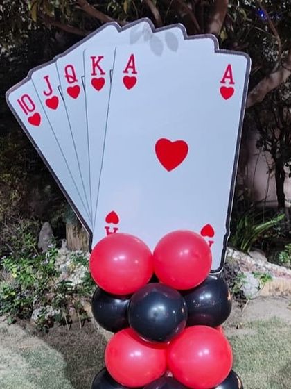A fun prop for a casino themed party, featuring a royal flush of hearts on a stand decorated with red and black balloons.