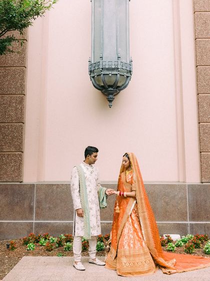 A moment of connection before the ceremony. Nisha in a traditional orange Sabyasachi Banarasi lehenga and Vishal in a contrasting ivory and mint sherwani by Jayanti Reddy. A beautiful blend of cultures and colors.