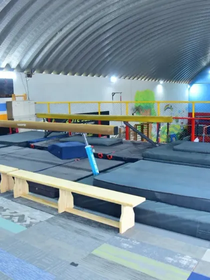This angle shows our setup with multiple balance beams, thick safety mats, and benches. We have all the necessary equipment for comprehensive gymnastics training.