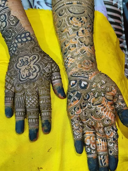 A fresh application of a bridal mehendi, showing the contrast between the dark paste and the skin. Notice the filled-in fingertips, a traditional element in bridal henna.