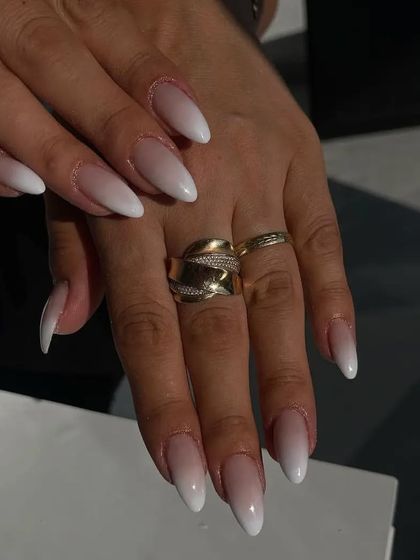 A classic white ombre on long, stiletto-shaped nails, offering a clean and elongated look.