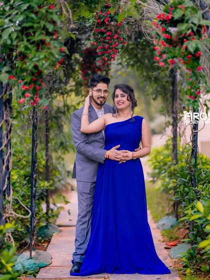 A classic couple's pose on a garden pathway under a floral arch, a timeless setting for a pre-wedding shoot.