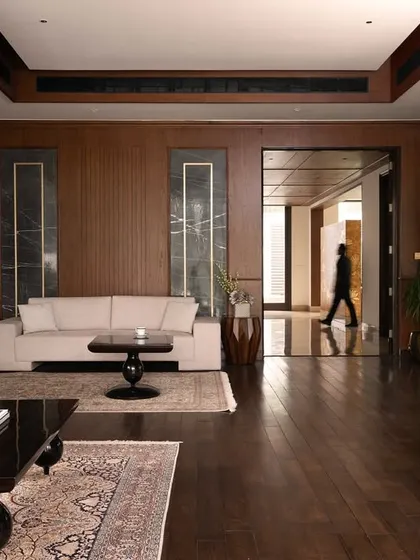The interior of the Mehalin Farm den, showing the rich wood paneling and its connection to the wider circulation spaces. The design prioritizes an open feel while maintaining distinct functional zones.