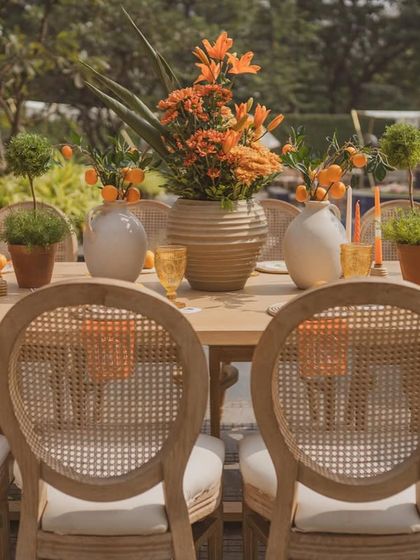 A beautifully set dining table with cane-back chairs, ready for guests to enjoy a meal in the 'Orange Orchard'.