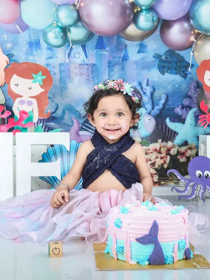 A full view of the mermaid-themed cake smash, with a beautiful cake and an under-the-sea backdrop full of balloons and characters.