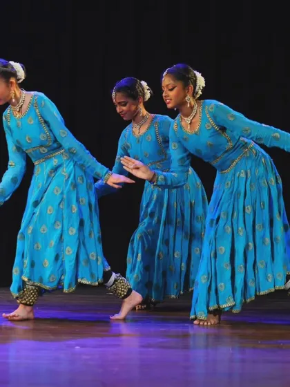This shot captures the perfect coordination and shared rhythm between the dancers as they move across the stage in their beautiful blue anarkalis.