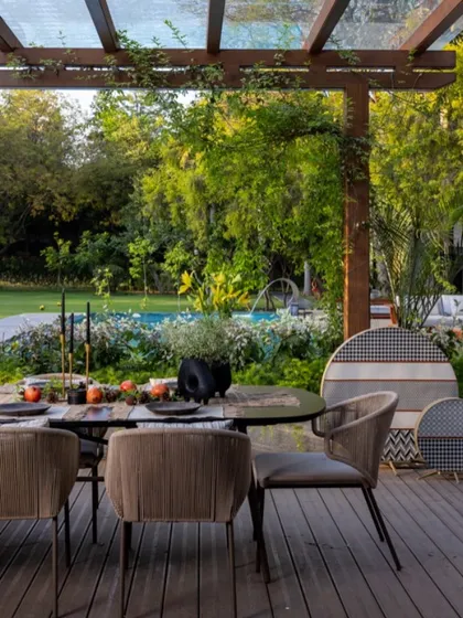 A closer view of the outdoor dining setup under a wooden pergola. We worked to harmonize the new landscape design with the existing trees to create a balanced and serene environment.