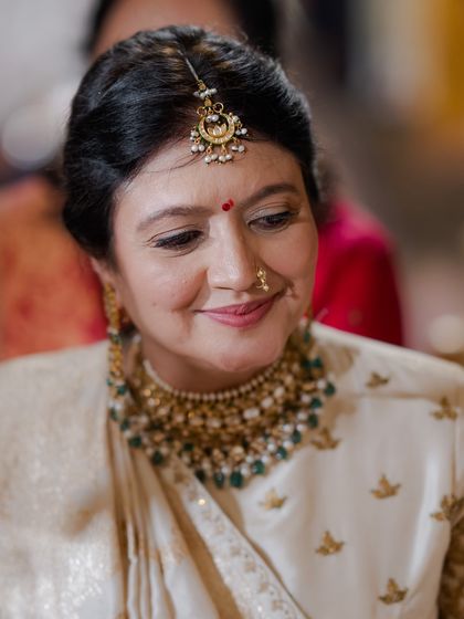 A portrait of the mother of the groom, showcasing her intricate polki and emerald necklace that beautifully complements her ivory saree. We assist families in selecting fine jewelry that becomes a future heirloom.