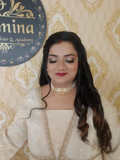 A close-up of the party makeup, showing the blended eyeshadow and the flawless base. The hair is styled with gentle waves, with some sections pinned back.