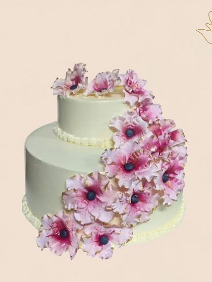 A cascade of delicate pink sugar flowers flows down this elegant two-tier cake. This handcrafted design adds a touch of sophisticated beauty to any anniversary or birthday party.