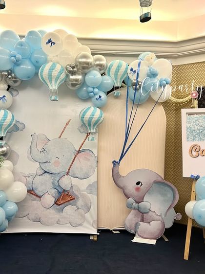The complete setup for the baby elephant themed naming ceremony, including floral arrangements and a custom easel.