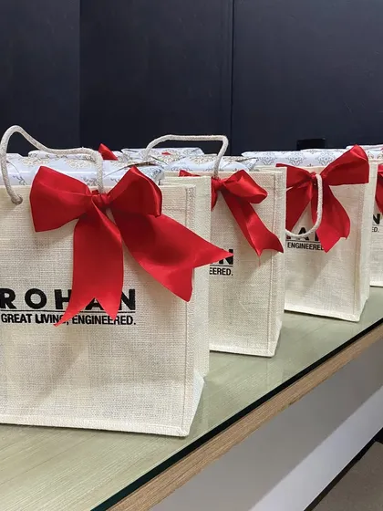 For a more rustic and eco-friendly option, we offer branded jute bags. These hampers for Rohan Builders are finished with a bright red bow, combining natural textures with a pop of brand color.