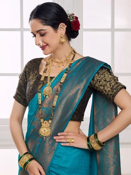 A smiling pose from the model in the blue saree, showcasing the long mangalsutra and matching earrings in a classic catalogue shot.