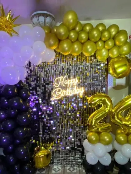 This shimmer backdrop combines a silver wall with black and gold balloons. We also added marquee numbers and a starburst foil balloon to complete the look for this 24th birthday.
