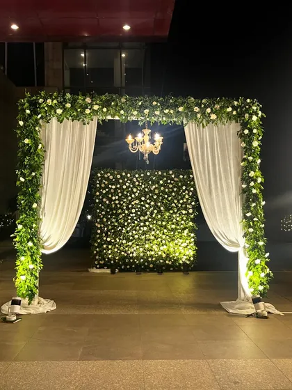A photo booth area with a lush wall of white flowers and greenery, framed by a floral arch. It’s the perfect spot for guests to capture memories.