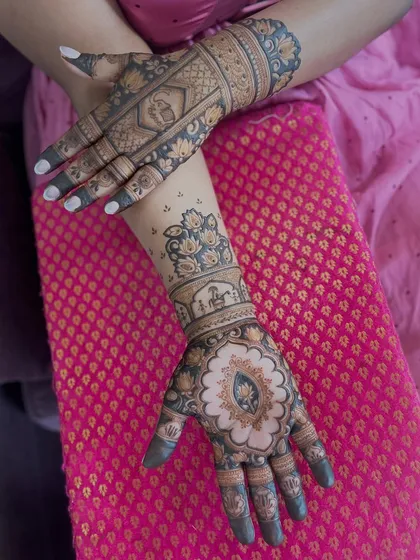 A unique bridal design with a large central mandala on the palm, surrounded by traditional motifs and a doli scene on the arm.