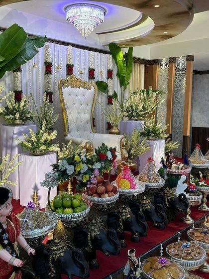 A stage with a white curtain backdrop, red rose accents, and large banana plants.